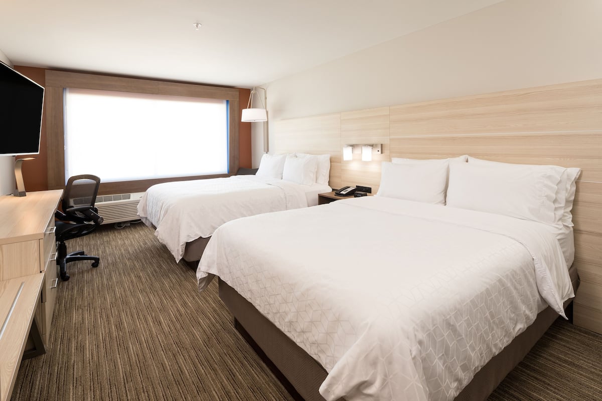Ein Hotelzimmer mit zwei Betten, einem Schreibtisch, einem Stuhl und einem Fernseher.