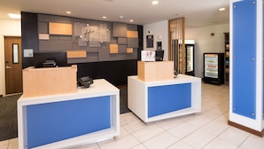 A reception area with two reception desks, a wall-mounted clock, a refrigerator, and a sign indicating a 'Stay Only' area. - Holiday Inn Express & Suites La Porte by IHG (La Porte)