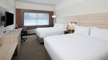 Habitación de hotel con dos camas, un escritorio, una silla, un televisor y una ventana con vistas al exterior.