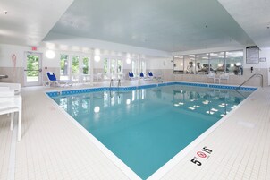 Una piscina interior con agua cristalina, líneas de profundidad marcadas y sillas de descanso.