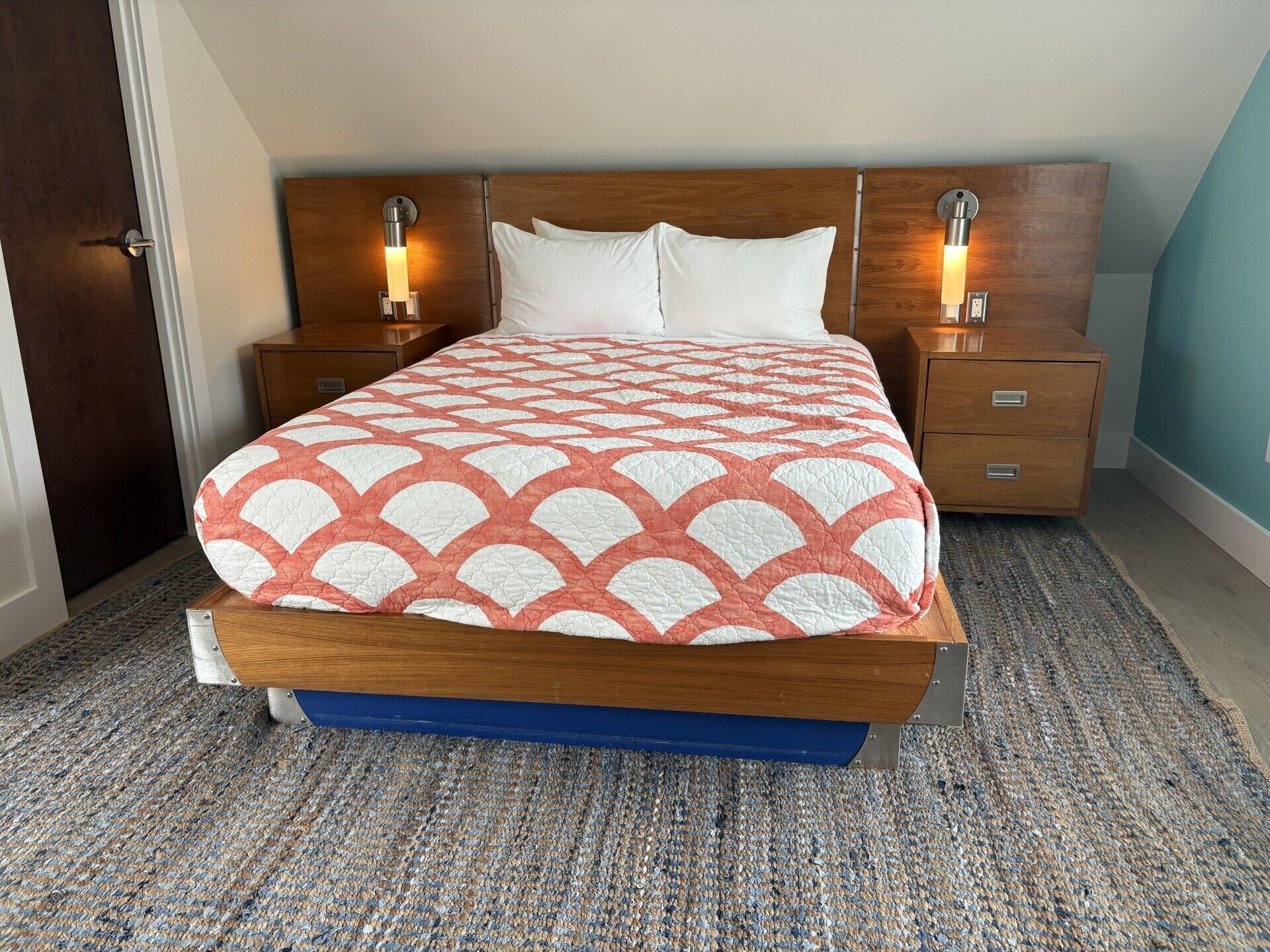 A neatly made bed with a patterned bedspread, two bedside tables with lamps, and a wooden headboard.