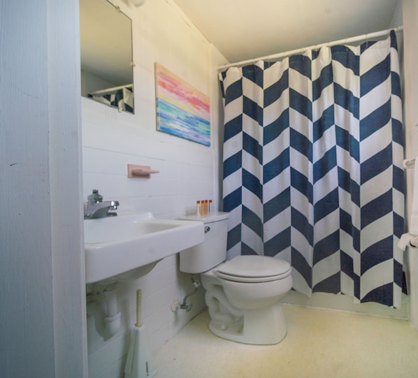Un baño con lavamanos blanco, inodoro y cortina de ducha con estampado en zigzag.