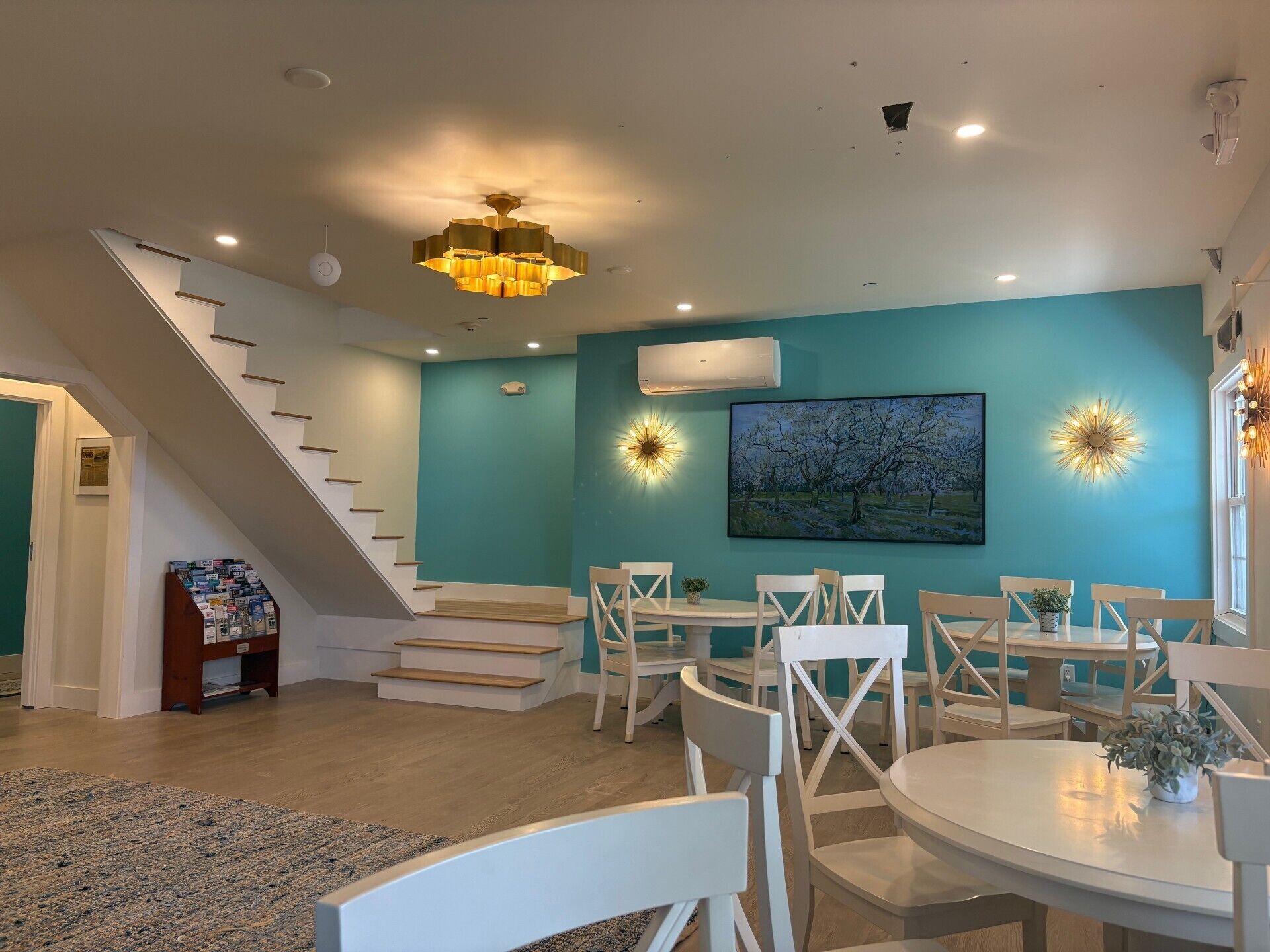 A modern interior with teal walls, white furniture, a staircase, and a chandelier.