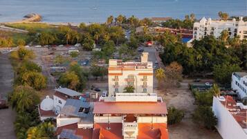 A hotel with a red roof, multiple balconies, and a view of the sea.