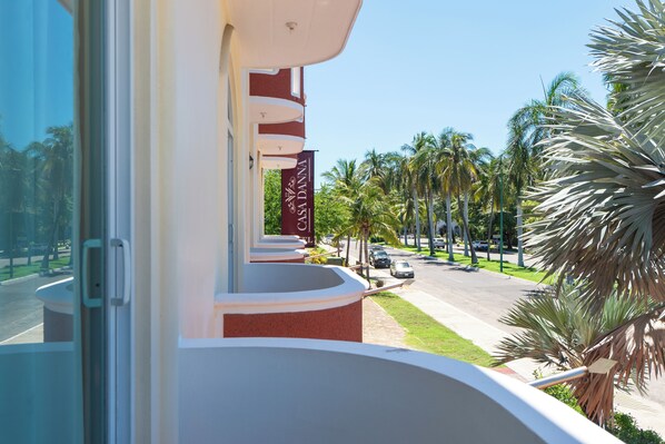 A hotel balcony with a view of palm trees and a street.