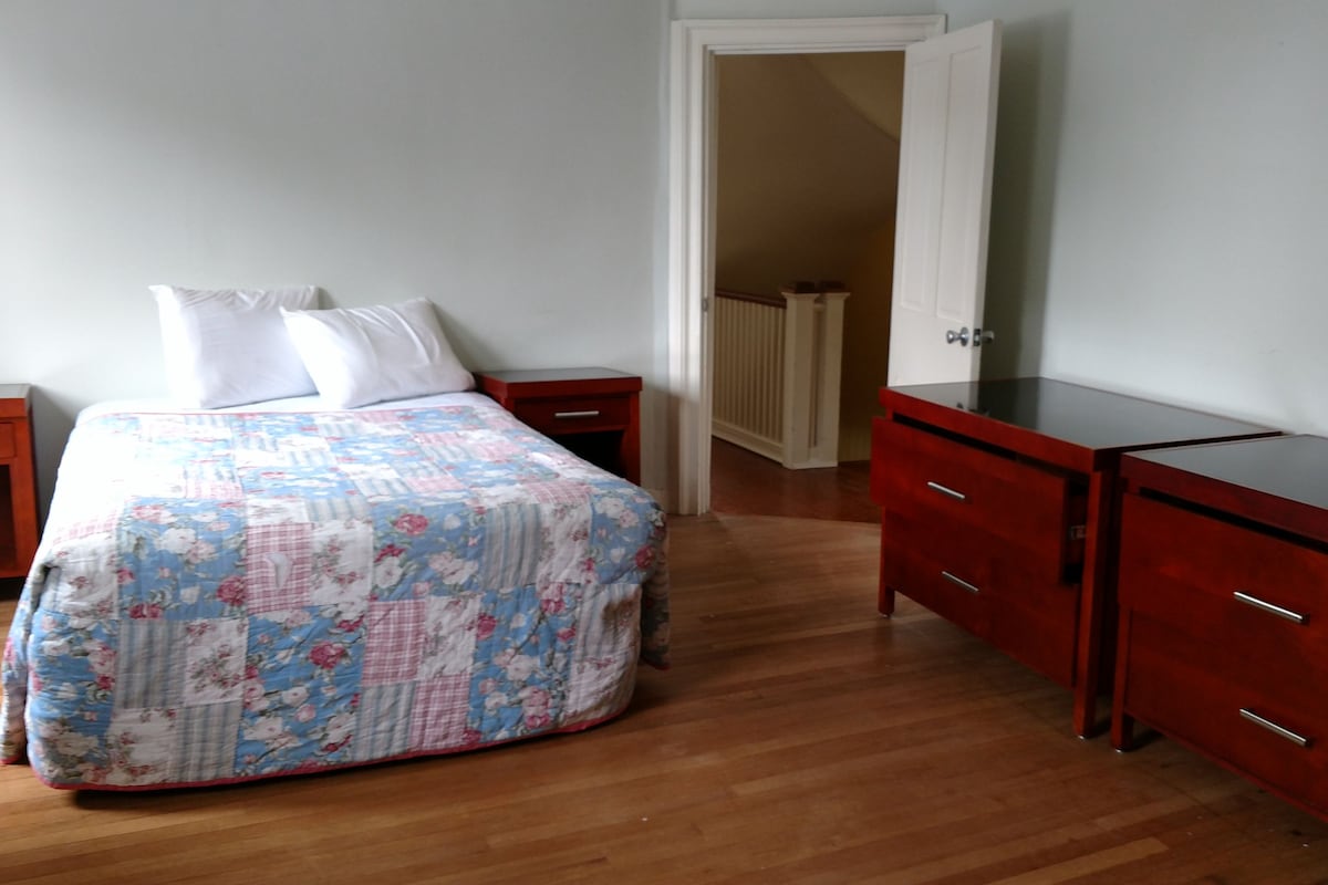 A bedroom with a bed, a TV, a dresser, and a nightstand.
