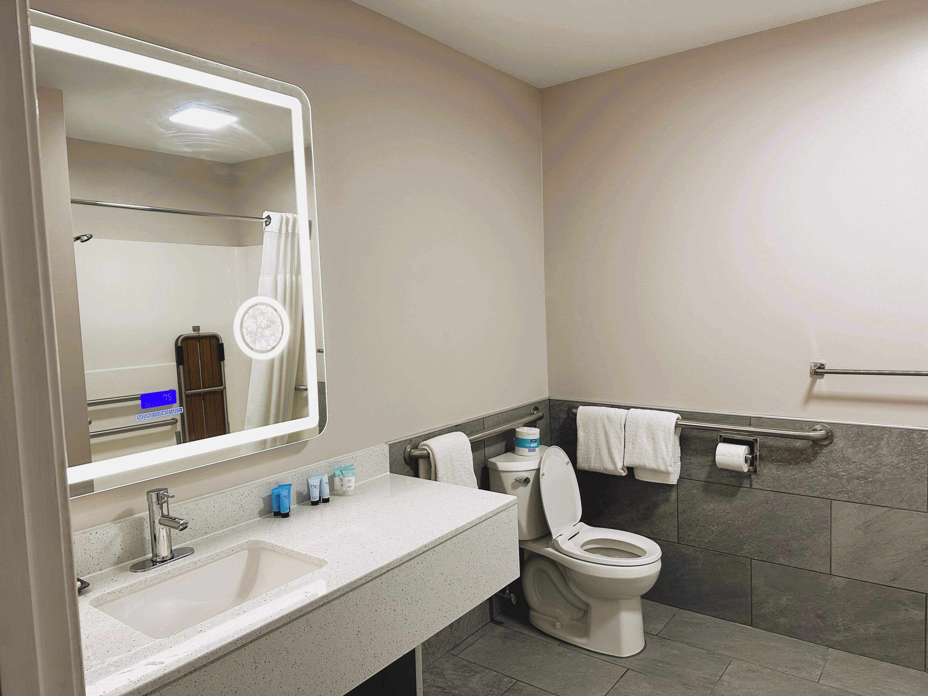 A modern bathroom with a sink, mirror, toilet, and towel rack.