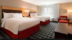 Een hotelkamer met twee bedden, een bureau, een stoel en een raam met gordijnen.