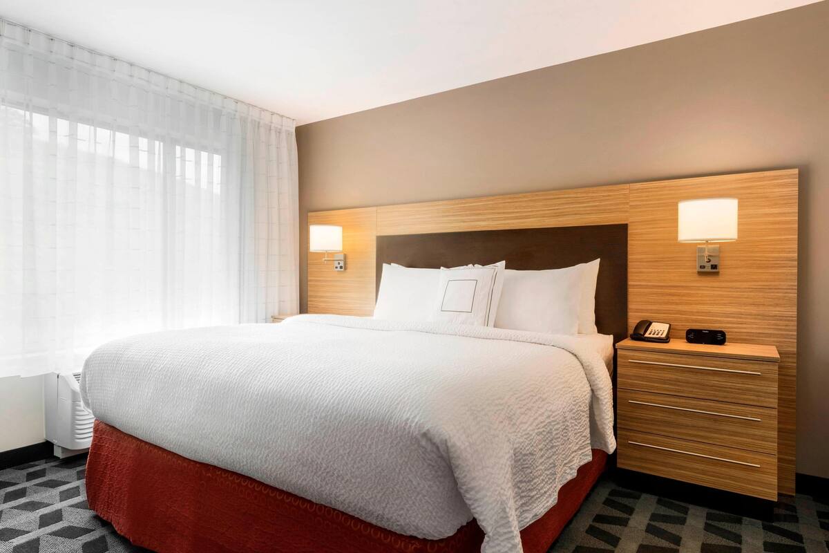Une chambre d’hôtel avec un grand lit, une table de chevet avec une lampe et un téléphone.