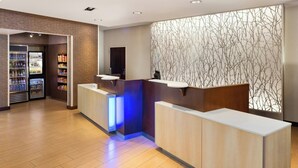 A reception area with a wooden floor, a counter with a digital screen, and a wall with a tree branch pattern. - Fairfield Inn & Suites by Marriott La Crosse Downtown (La Crosse)