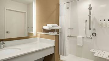 Un baño moderno con un lavamanos grande, una ducha con puerta de vidrio y un perchero para toallas.