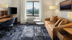 A hotel room with a large window, a TV, a desk, a chair, a sofa, and a lamp. - Fairfield Inn & Suites by Marriott La Crosse Downtown (La Crosse)