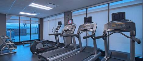 Un gimnasio con cintas de correr, máquinas de pesas y una máquina de remo.