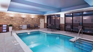 An indoor swimming pool with a stone wall, seating area, and large windows. - Fairfield Inn & Suites by Marriott La Crosse Downtown (La Crosse)