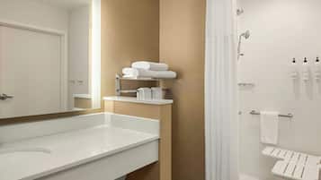 A modern bathroom with a large mirror, white sink, towel rack, and shower area.