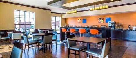 A modern hotel lobby with a bar area, seating arrangements, and a view of the outside.