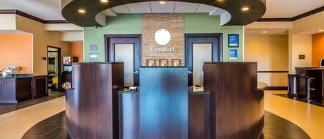 A reception area with a central desk, two doors, and a circular light fixture above.