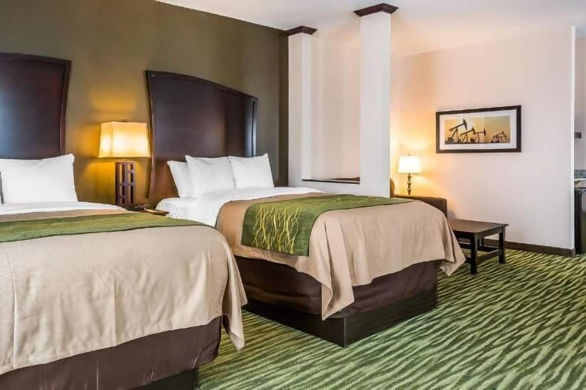 Habitación de hotel con dos camas, un escritorio y una silla.
