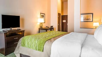 Een hotelkamer met een bed, een televisie, een bureau met lamp en een deur.