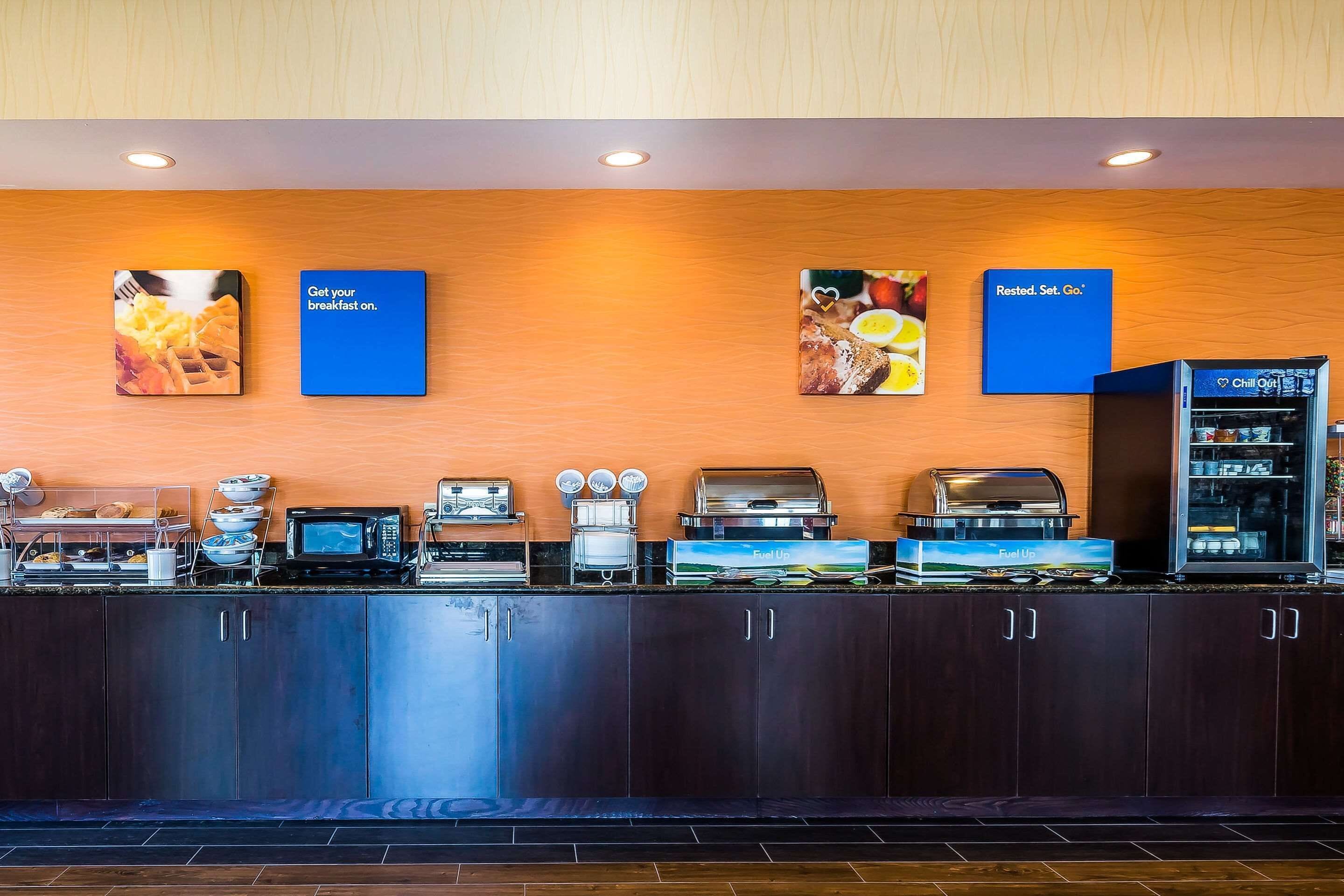 A breakfast bar with a microwave, toaster, and coffee maker. There are signs for breakfast and a chilled-out beverage.