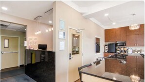 A modern kitchen with wooden cabinets, a large island, and a built-in microwave. - Albertan Inn (Fox Creek)