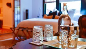 A neatly arranged table with a bottle, two glasses, and a salt shaker in a hotel room. - The English Merchant's Inn (Waxahachie)