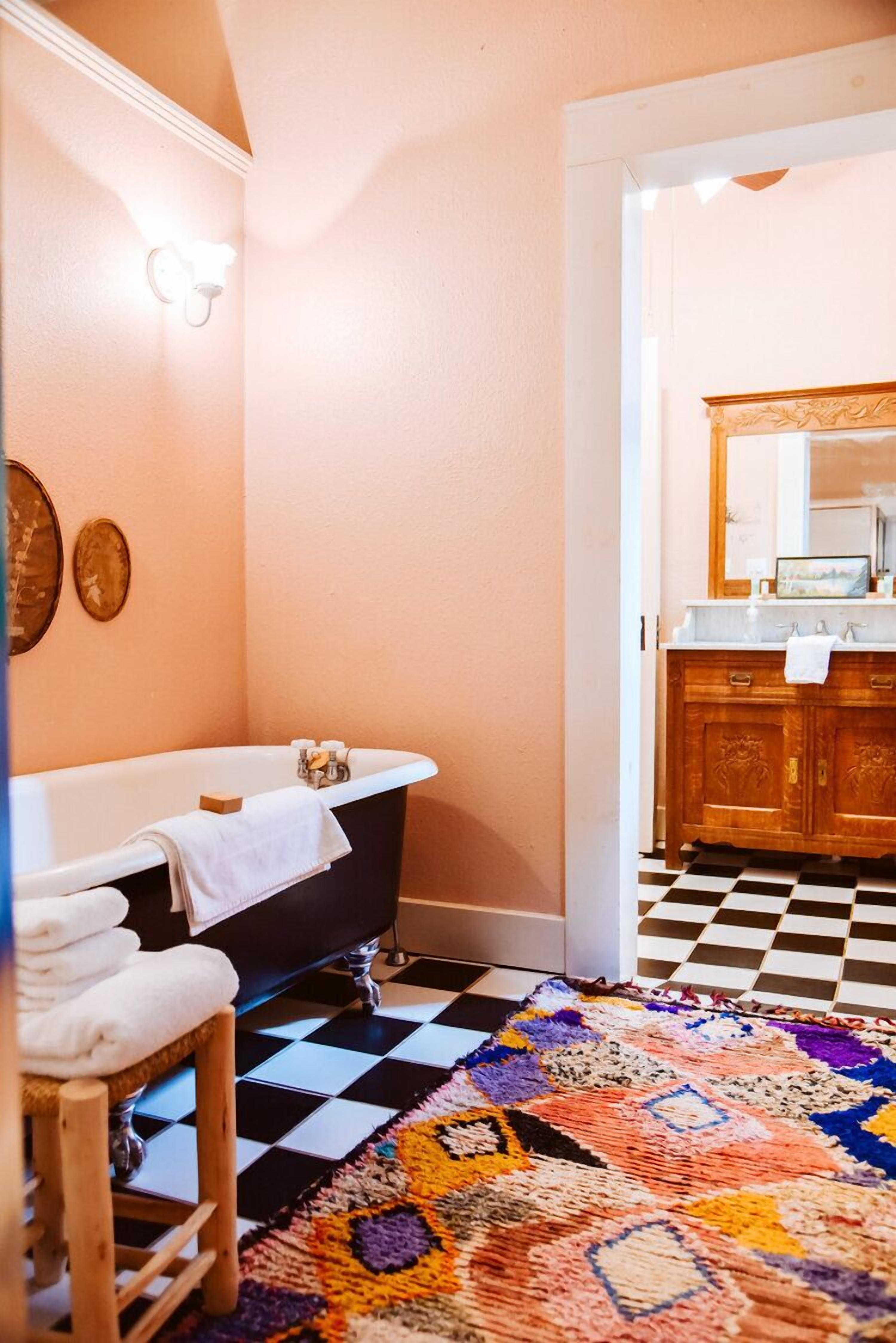 Une salle de bain avec une baignoire noire, un meuble-lavabo en bois et un carrelage à motifs à carreaux.