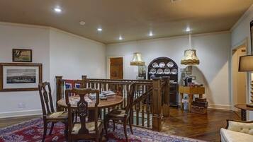 Un comedor con una mesa y sillas de madera, un tapete estampado y una escalera que lleva a otra habitación.