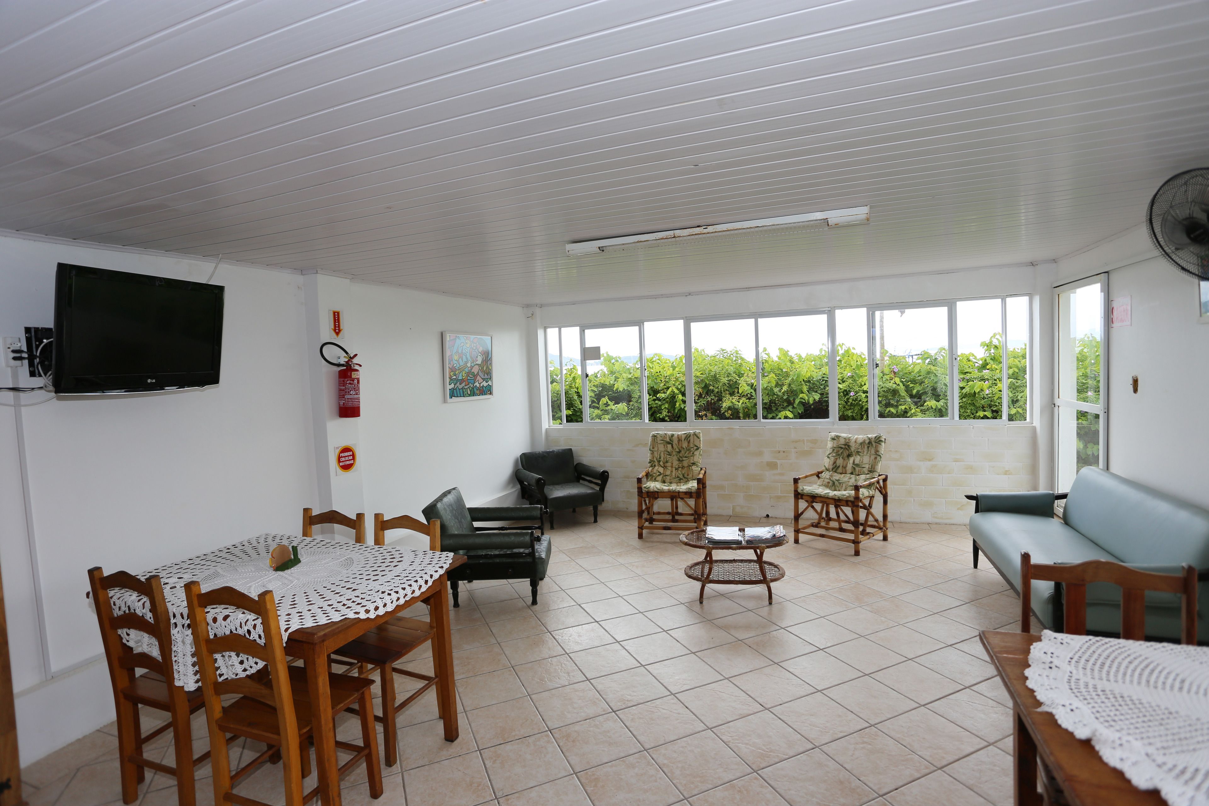 A spacious living area with a dining table, chairs, sofas, and a television.