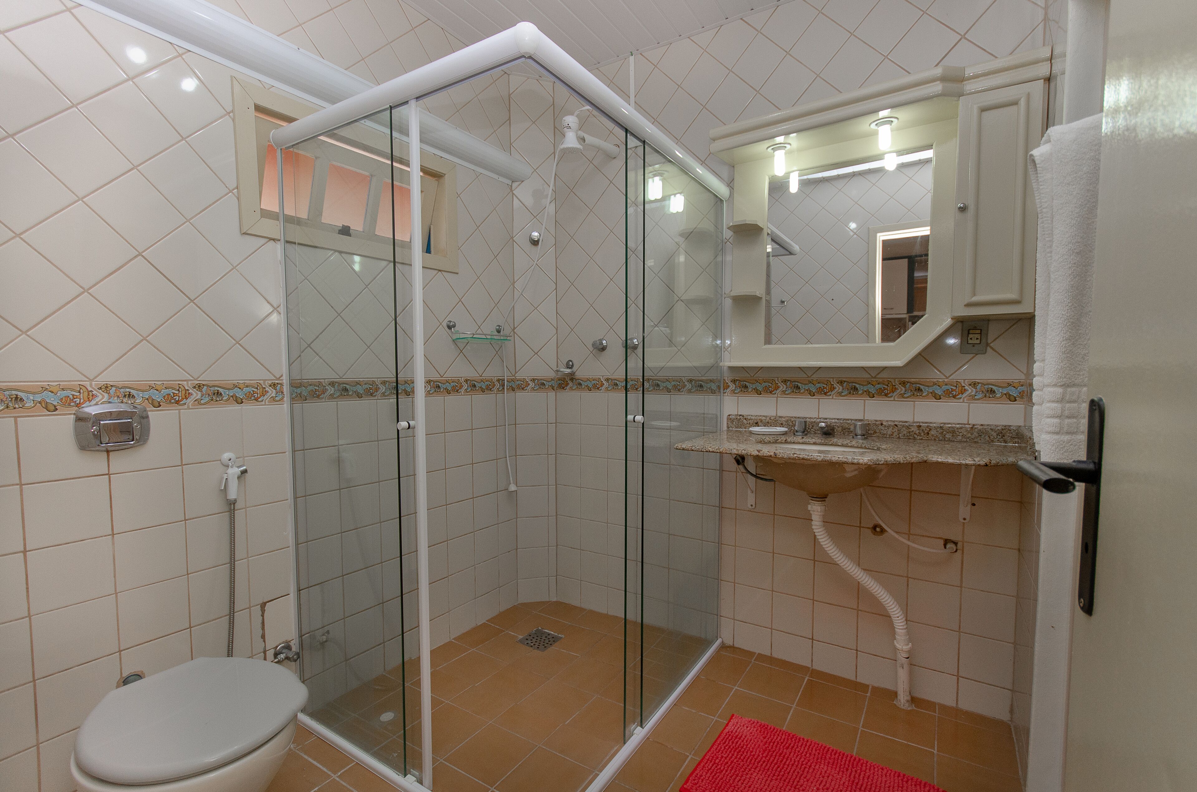 Une salle de bain avec une douche à parois de verre, des toilettes et un lavabo avec un miroir au-dessus.