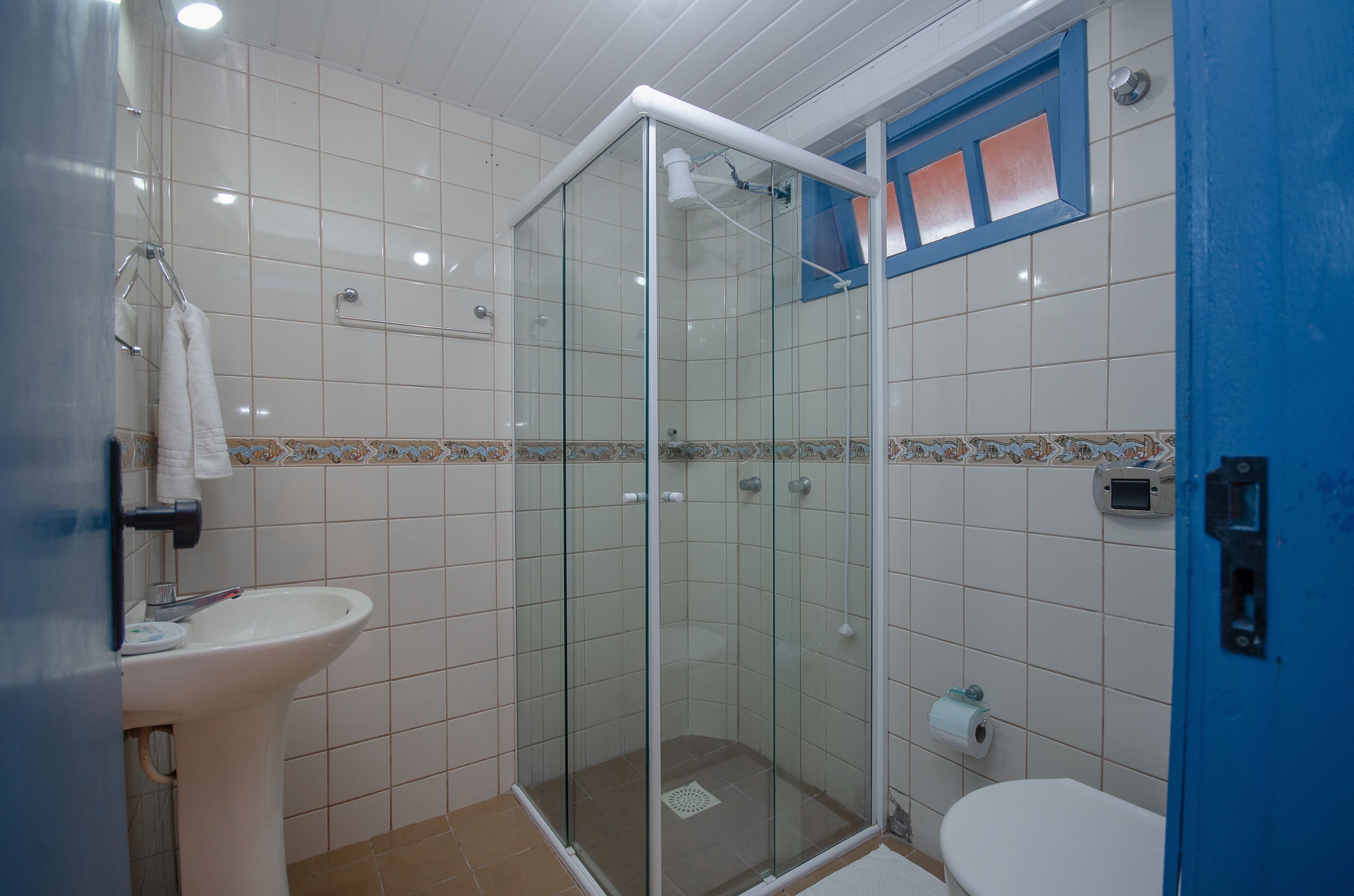 Ein Badezimmer mit einer gläsernen Duschkabine, einem weißen Waschbecken und einer Toilette.