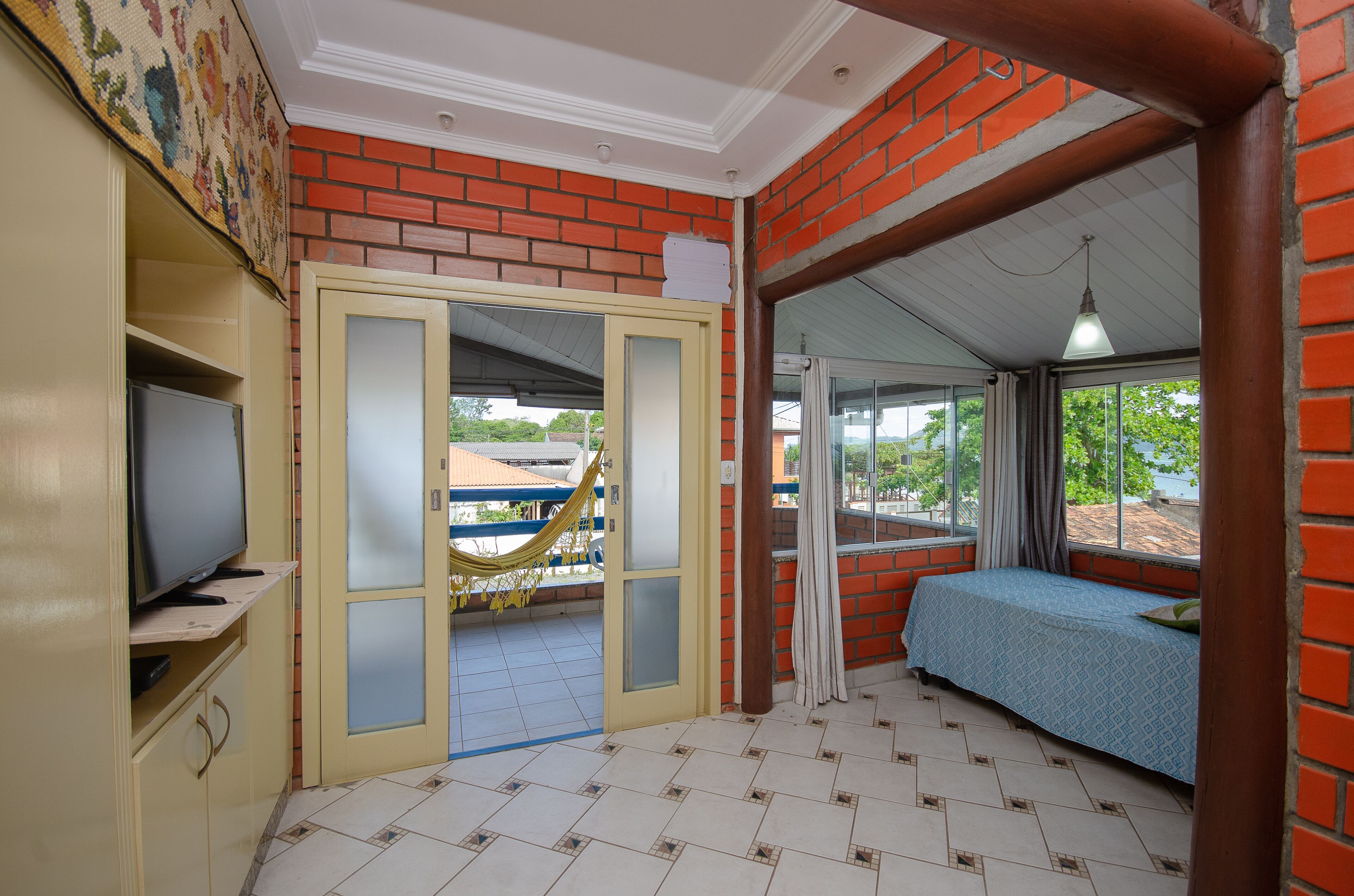 A compact room with a bed, a television, and a hammock.