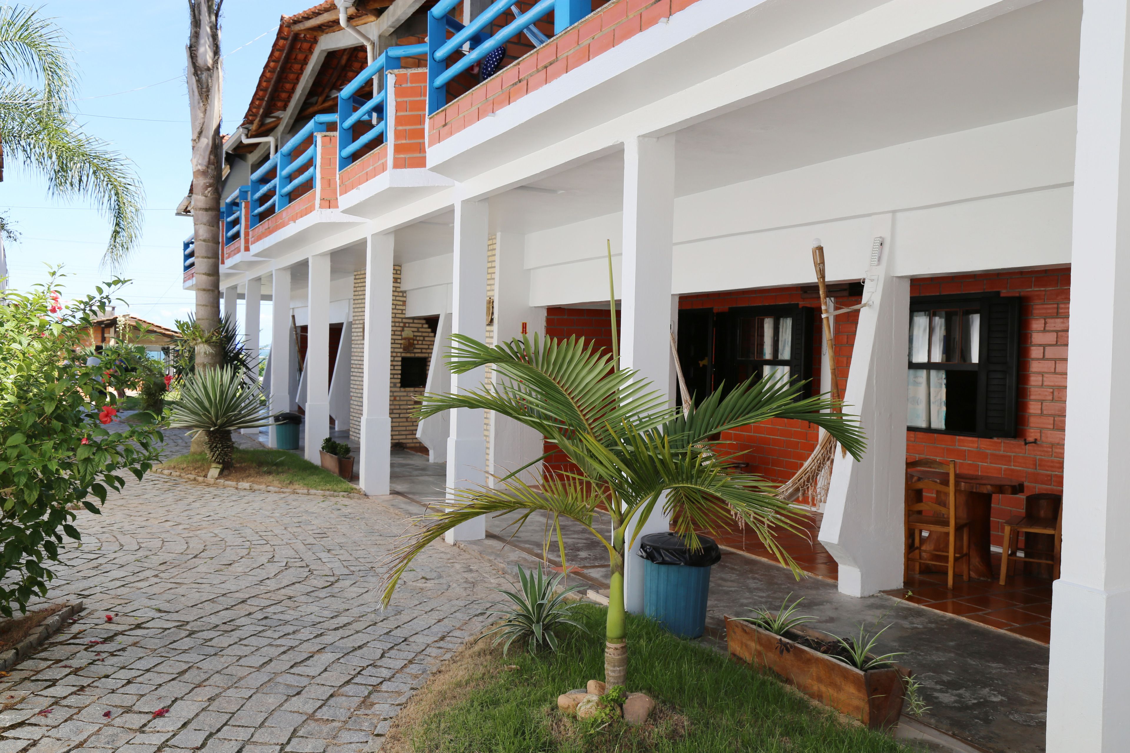 Un hotel con un área exterior techada, fachada de ladrillo y una palmera.