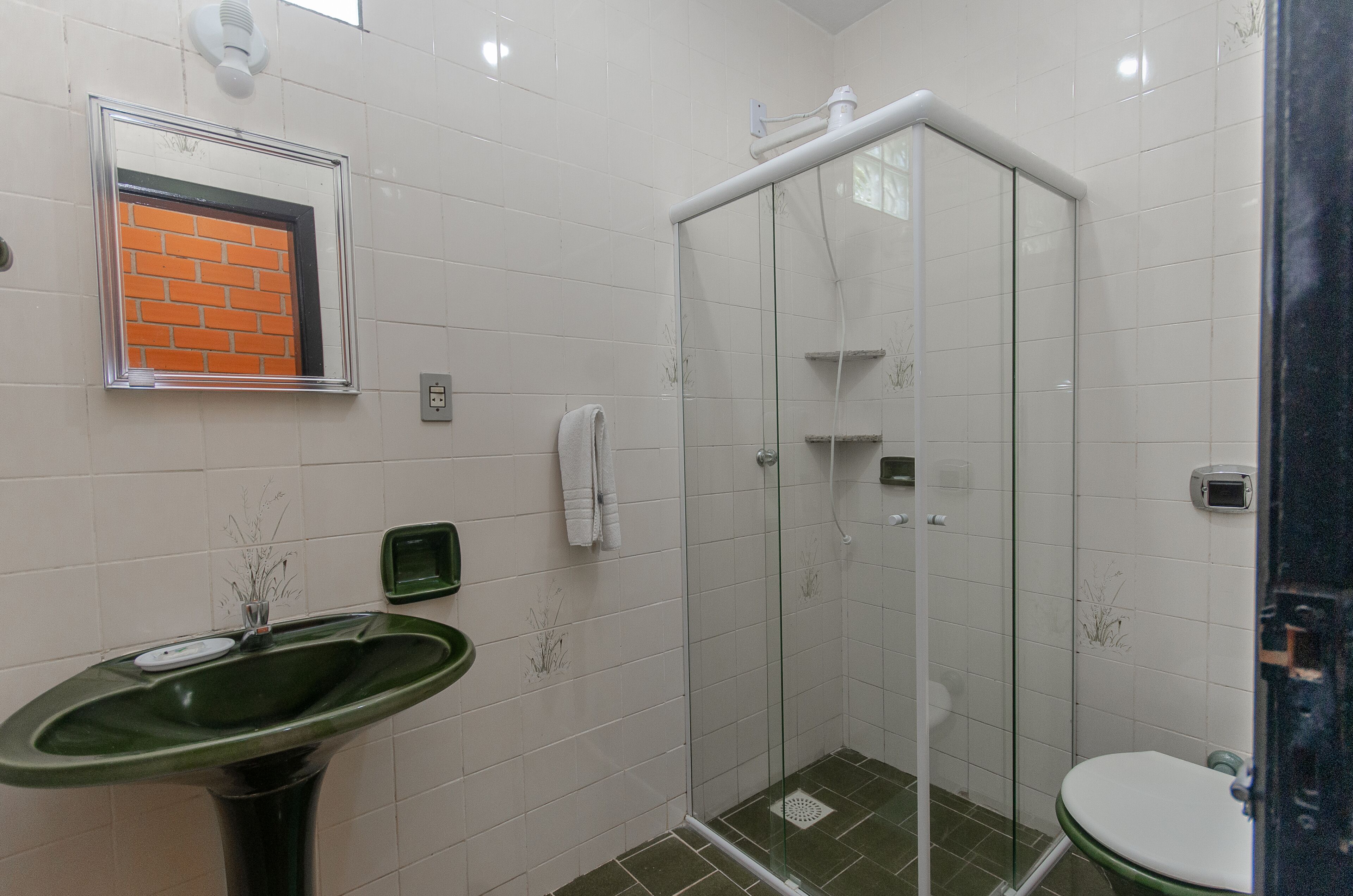 A bathroom with a green sink, a glass shower enclosure, and a white toilet.