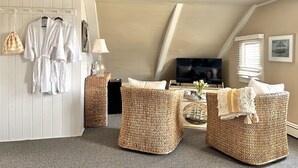 A cozy room with a TV, wicker furniture, and a white wall with a hanging robe.