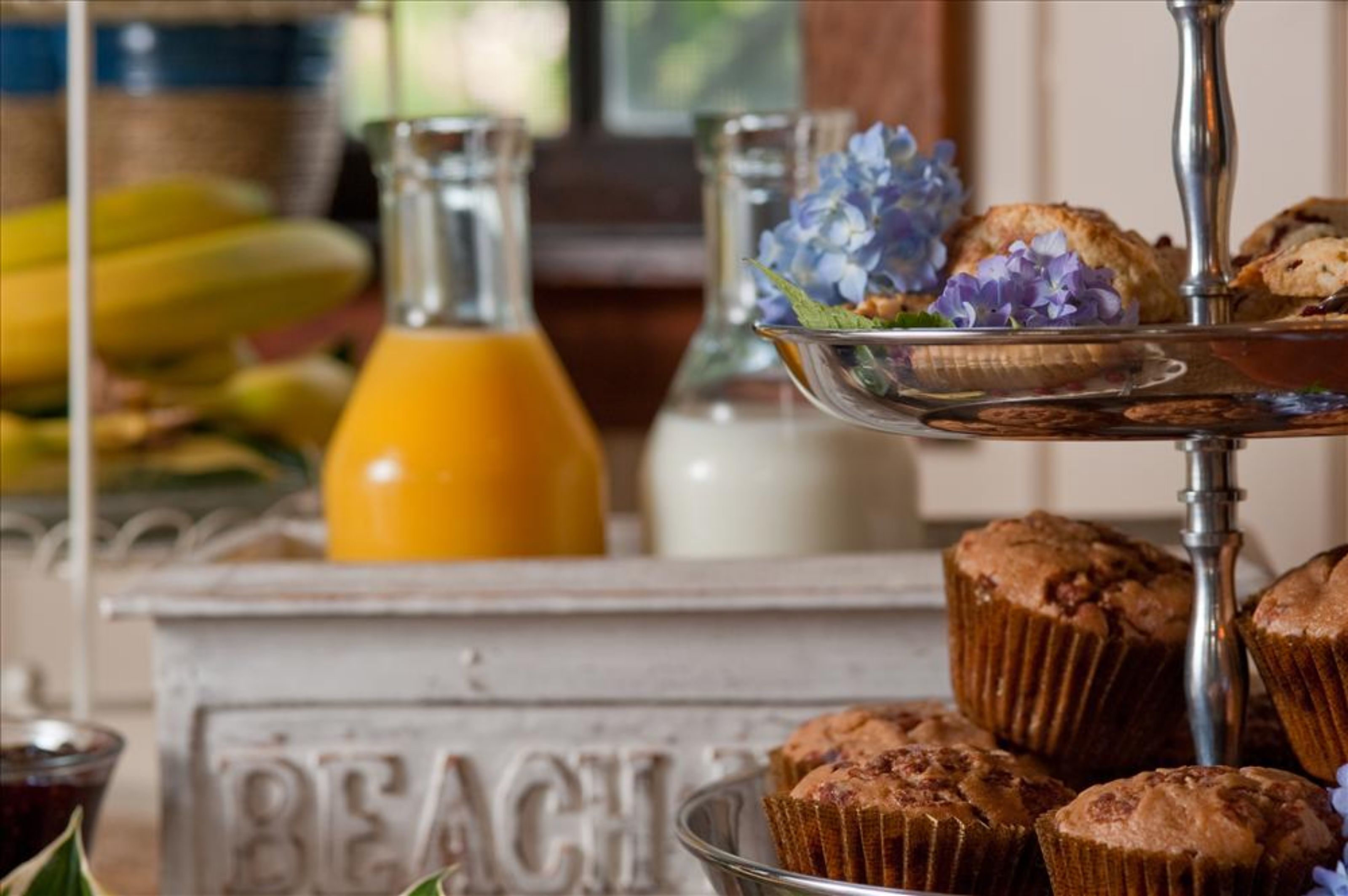 Ein Frühstücksbuffet mit Muffins, einer Orangensaftflasche und einer dekorativen Karaffe.