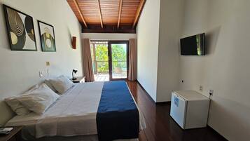 Una habitación de hotel con cama, escritorio, silla, televisor y un refrigerador pequeño.
