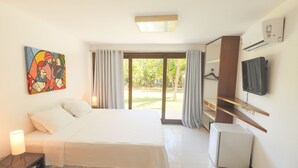 Habitación de hotel con una cama, un escritorio, un televisor, un refrigerador pequeño y un cuadro en la pared.