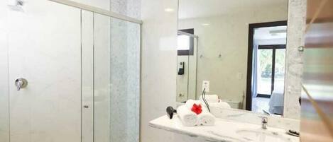A modern bathroom with a glass shower enclosure, a marble sink, and a large mirror.