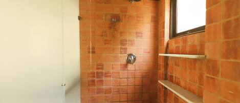 Une douche avec un mur carrelé, une fenêtre et une porte blanche.