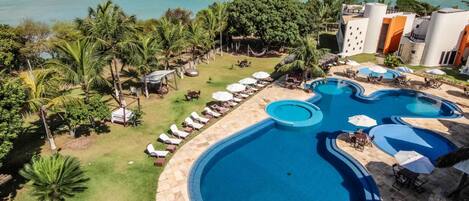 Un resort con un amplio espacio de piscina, sillas de descanso y vistas al océano.