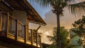 Una casa de dos pisos con un balcón, una palmera y un césped bien cuidado.