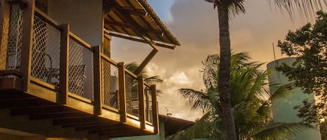 Una casa de dos pisos con un balcón, una palmera y un césped bien cuidado.