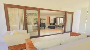 Una sala de estar moderna con un amplio ventanal corredero que da a un comedor.