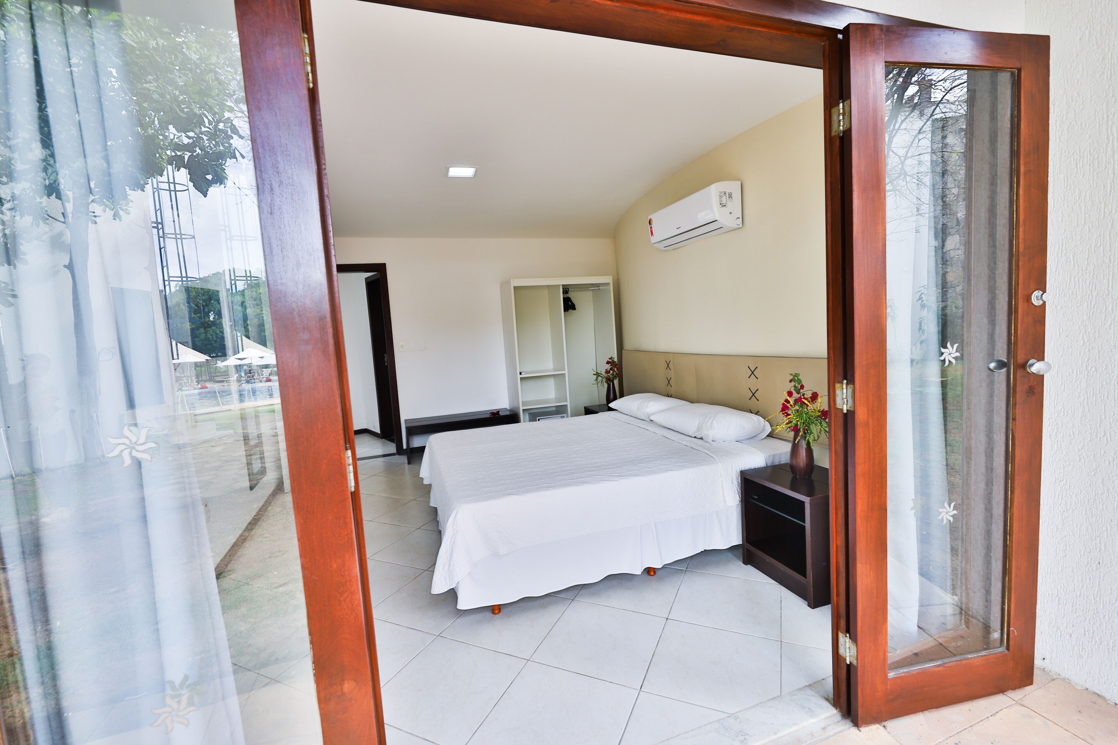 Une chambre d’hôtel avec un grand lit, une table de chevet, une armoire et un appareil de climatisation fixé au mur.