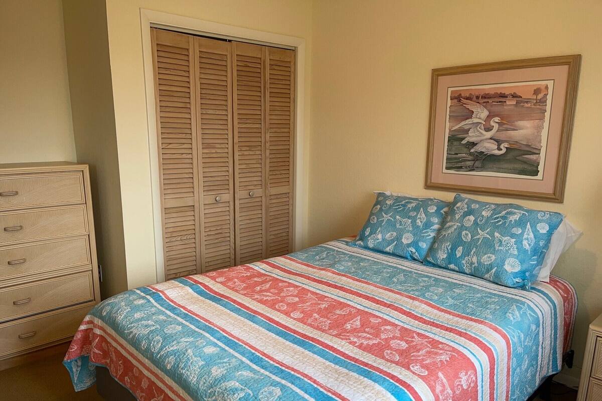 Ein Schlafzimmer mit Bett, Kommode, Schrank und einem gerahmten Bild an der Wand.