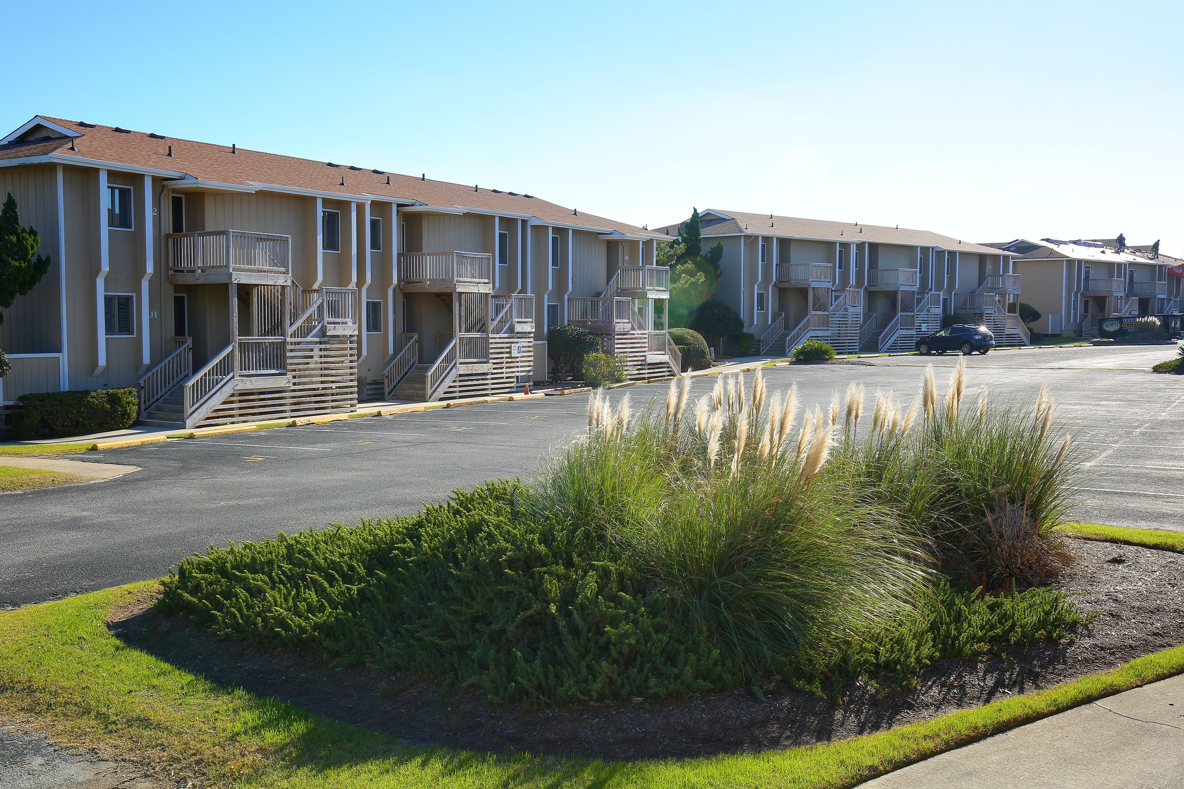 A row of multi-story apartment buildings with balconies and a parking lot in the foreground.