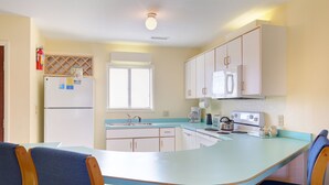 A kitchen with a built-in island, white cabinets, a refrigerator, a microwave, and a stove. - Sea Scape Beach and Golf Villas (Kitty Hawk)