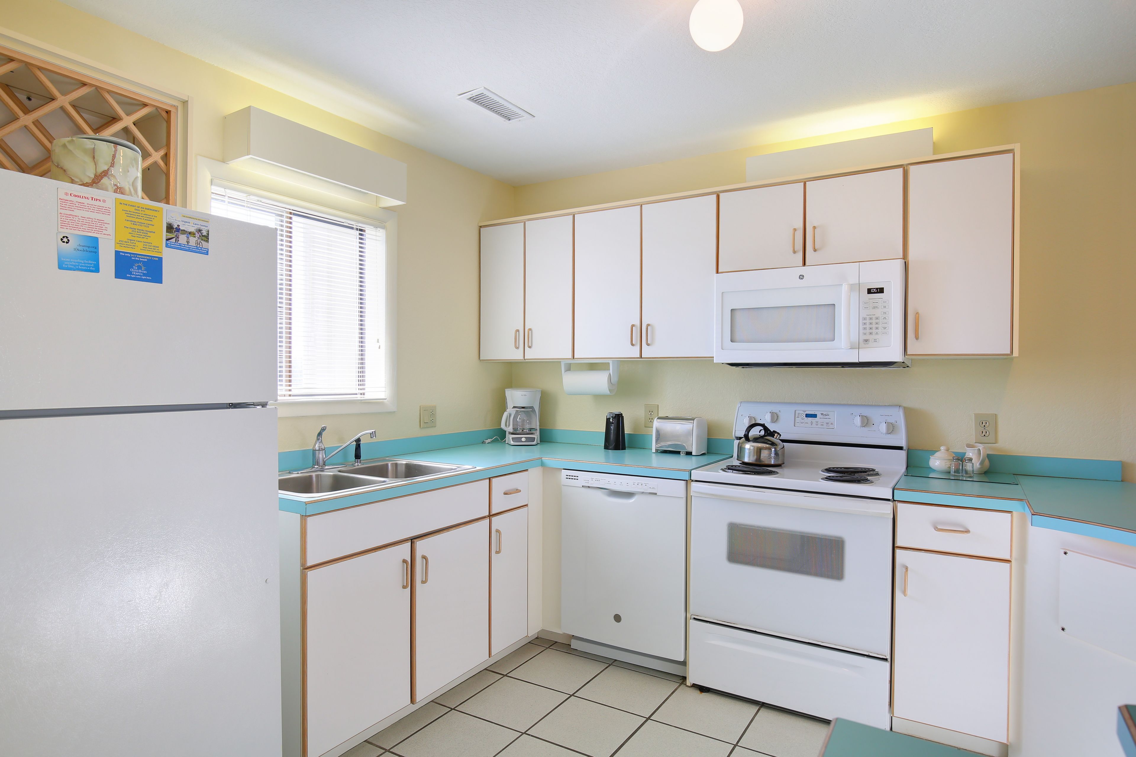 A compact kitchen with white cabinets, a microwave, a dishwasher, and a stove.