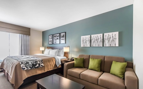 A hotel room with a bed, a sofa, a coffee table, and wall art.